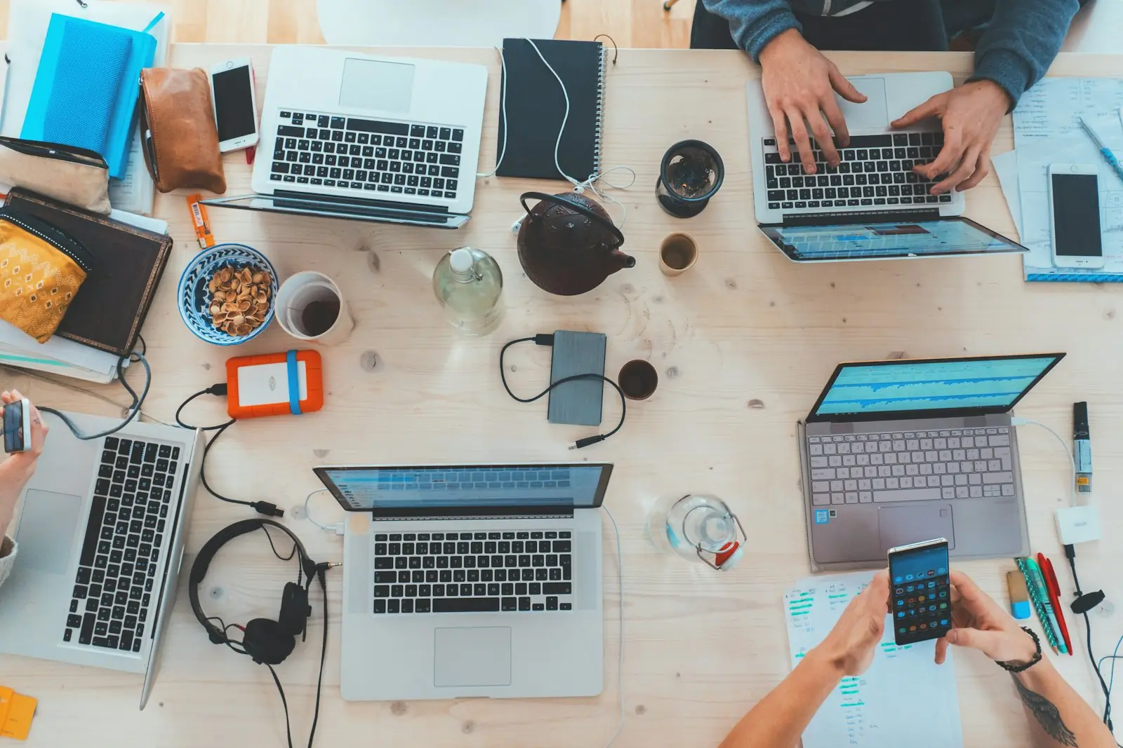 Laptops, notebooks and phones on a shared desk during a marketing planning session